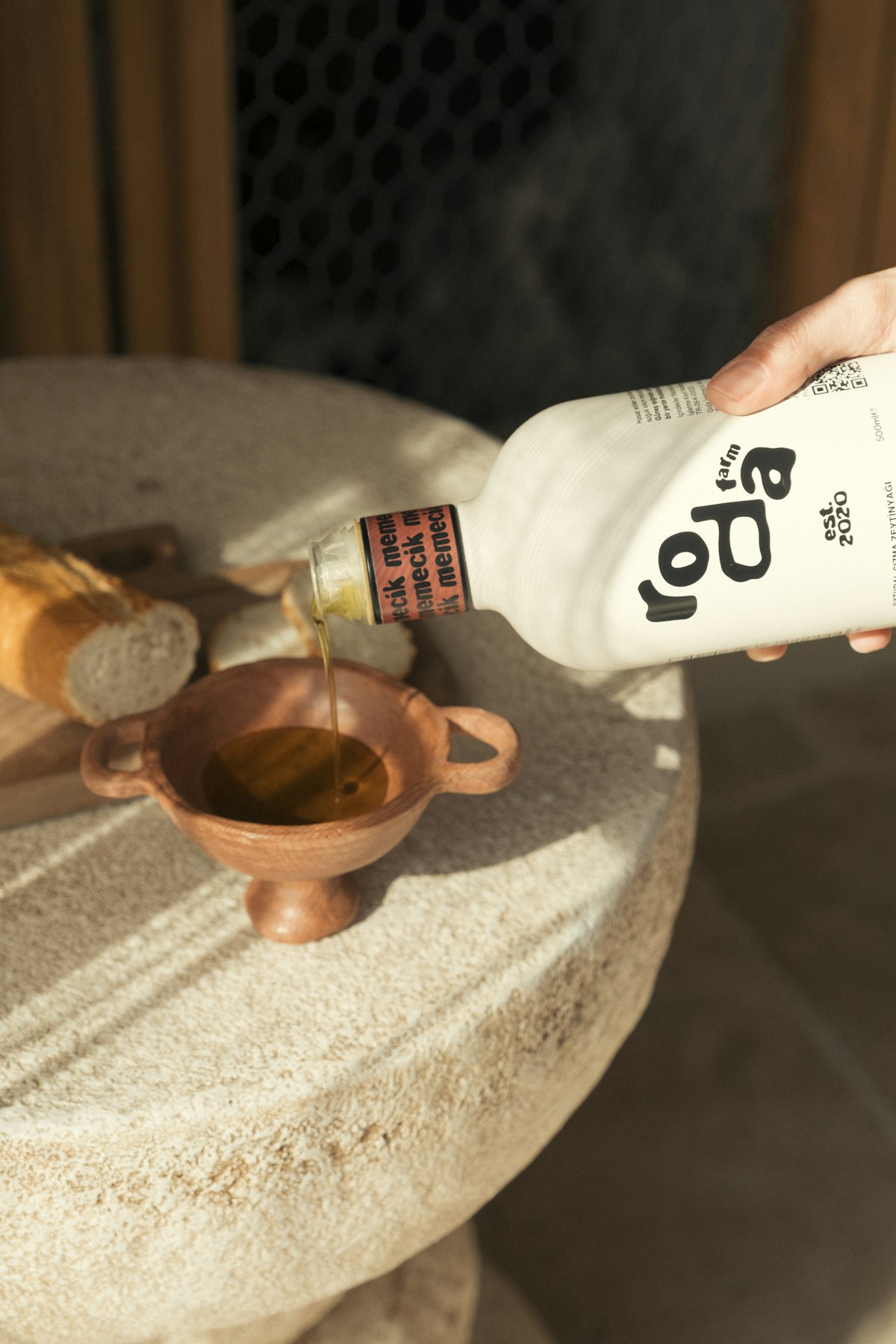 A hand pouring olive oil into a dish with bread